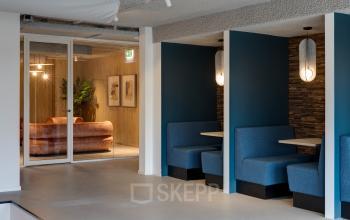 Stylish office space at Vanadiumweg 11, Amersfoort Isselt featuring cozy blue booths and modern decor, perfect for office space rental. Includes a well-lit lounge area visible in the background.