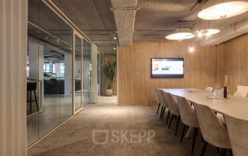 Modern conference room at Vanadiumweg 11, Amersfoort Isselt, featuring a long table, cushioned chairs, and a mounted TV, perfect for office space rental.
