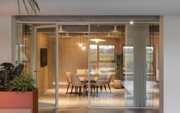 Contemporary, well-lit conference room with glass walls in Amersfoort Isselt's Vanadiumweg 11 office building; ideal for office space rental. Features a round table, chairs, and indoor plants.