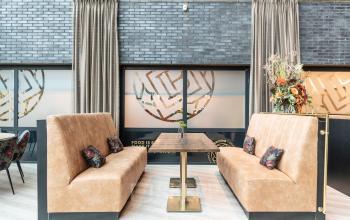 Stylish seating area in a modern office lounge at Prof. W.H. Keesomlaan 12, Amstelveen, featuring plush booths and a central table.