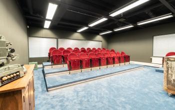 Office meeting space at Prof. W.H. Keesomlaan 12, Amstelveen, featuring red theater-style seating on a blue carpeted floor.