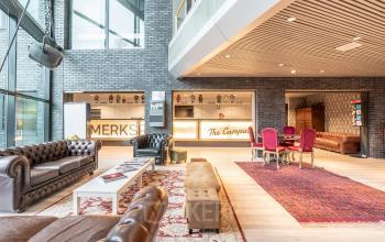 Spacious lounge area of an office to rent at Prof. W.H. Keesomlaan 12, Amstelveen. Features comfortable seating, elegant rugs, modern decor, and a bright atmosphere.