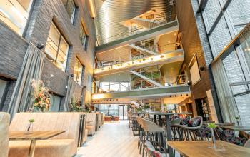 Spacious, modern interior of an office building located at Prof. W.H. Keesomlaan 12, in Amstelveen, featuring multiple floors, open seating areas, and abundant natural light. Ideal office space rental option.