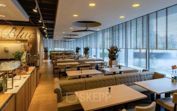Modern dining area in an office building at Professor E.M. Meijerslaan 1, Amstelveen, featuring well-arranged tables and natural lighting, ideal for casual meetings or breaks. Explore available office space rental options.