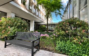 Exterior view of the office building at Professor E.M. Meijerslaan 1, Amstelveen, featuring a tranquil garden with a bench, ideal for breaks. Perfect for those seeking office space rental in a pleasant environment.