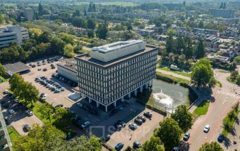 Aerial view of office building at Professor E.M. Meijerslaan 1, Amstelveen, featuring ample parking and scenic surroundings. Ideal for those seeking office space rental in a well-connected location.