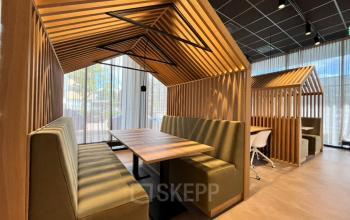 Modern office space at Professor E.M. Meijerslaan 1 in Amstelveen featuring stylish wooden booths with green seating, perfect for collaborative work or meetings. Discover this inviting office space rental option in a sleek environment.