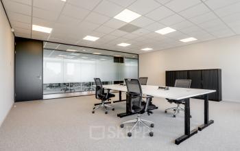 Furnished office space for rent at De Gondel 1, Amstelveen, featuring modern desks and chairs in a bright, carpeted room with glass partitions.
