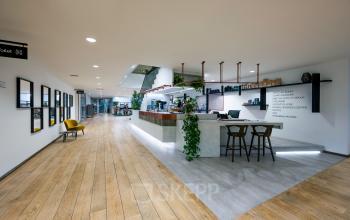 Spacious reception area at De Gondel 1, Amstelveen with contemporary decor, wooden flooring, and a neatly organized desk for office space rental inquiries.