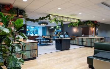 Modern office space rental at De Gondel 1, Amstelveen, featuring a stylish canteen area with seating and greenery.