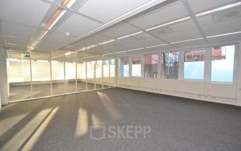 Bright, unfurnished office space rental available at Stroombaan 4, Amstelveen, featuring large windows and glass partitions.