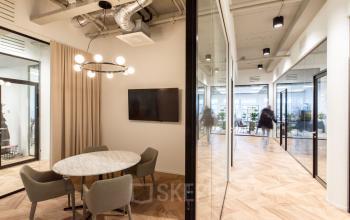 Modern office space in Amsterdam Amstel Business Park, featuring glass walls, a round meeting table with chairs, and a wall-mounted TV at H.J.E. Wenckebachweg 123.