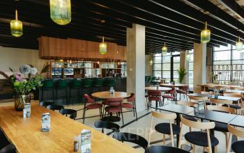 Modern office space rental at Joan Muyskenweg 137 in Amsterdam Amstel Business Park, featuring a stylish, furnished open floor plan with contemporary seating and elegant lighting fixtures.