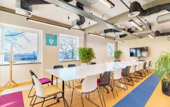 Modern conference room in Amsterdam Amstel Business Park with large tables and chairs, bright lighting, and plants, suitable for office space rental.