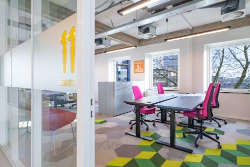 Bright workspace with modern furniture at Willem Fenengastraat 2, Amsterdam Amstel Business Park. Features colorful chairs and geometric carpet tiles.