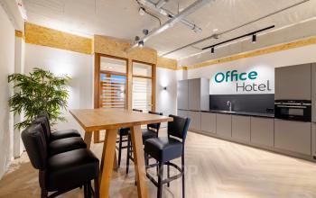 Modern furnished workspace at Joan Muyskenweg 82, featuring a sleek wooden high table and kitchen facilities, perfect for office space rental in Amsterdam Amstel Business Park.