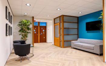 Modern office lounge area with a sofa and chairs, located at Joan Muyskenweg 82 in Amsterdam Amstel Business Park, available for office space rental.