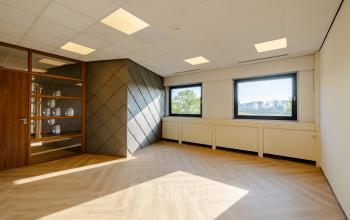 Spacious unfurnished office space at Joan Muyskenweg 82, Amsterdam Amstel Business Park, featuring wooden flooring and large windows offering natural light, ideal for office space rental.