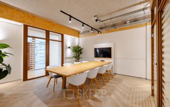 Modern conference room at Joan Muyskenweg 82, featuring a sleek wooden table, white chairs, and a large screen, ideal for dynamic office space rental in Amsterdam Amstel Business Park.