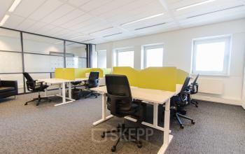 Open workspace with modern desks and office chairs, partitioned by lime-green dividers at Joop Geesinkweg 901-999, Amsterdam Amstel Business Park.