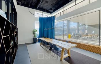 Bright, modern conference room with a long wooden table and high windows at Joan Muyskenweg 22, Amsterdam Amstel Business Park, available for office space rental.