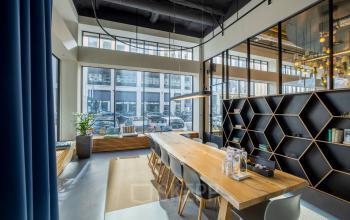 Modern office space with long wooden table, chairs, bookshelf, and large windows at Joan Muyskenweg 22 in Amsterdam Amstel Business Park.