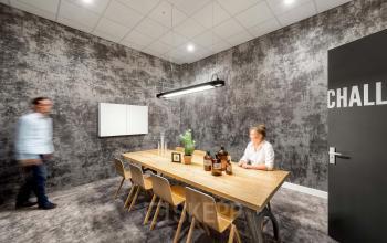 Modern conference room at Joan Muyskenweg 22, Amsterdam Amstel Business Park, featuring a large wooden table, chairs, and contemporary decor. The office space rental offers a professional meeting environment.