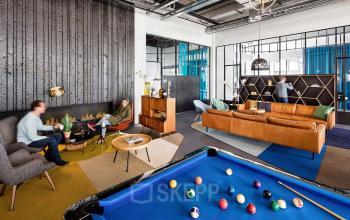 Modern lounge area in an office building at Joan Muyskenweg 22, Amsterdam Amstel Business Park, featuring stylish furniture and a pool table for employee relaxation.