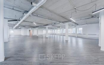 Spacious and modern open floor plan office to rent at H.J.E. Wenckebachweg 90-108, Amsterdam Amstel Business Park, featuring polished floors and exposed ceiling pipes with ample natural light.