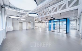 Modern office space rental at H.J.E. Wenckebachweg 90-108, Amsterdam Amstel Business Park, featuring large circular ceiling lights and a blue meeting pod.