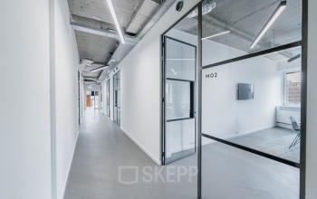 Modern hallway in office building at H.J.E. Wenckebachweg 90-108, Amsterdam Amstel Business Park, Amsterdam, featuring enclosed glass-walled office to rent.