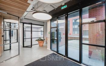 Modern office entrance at H.J.E. Wenckebachweg 90-108, Amsterdam Amstel Business Park with large glass doors and indoor plants.