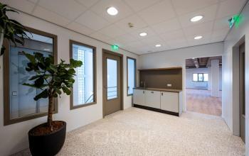 Modern office interior at Joop Geesinkweg 601, Amsterdam Amstel Business Park, featuring a small kitchenette and potted plant.