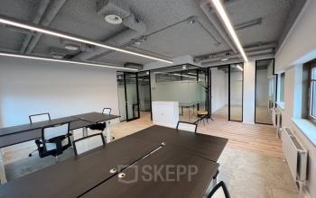 Modern office space rental with dark tables, chairs, and glass-walled meeting areas at Joop Geesinkweg 601, Amsterdam Amstel Business Park, Amsterdam.