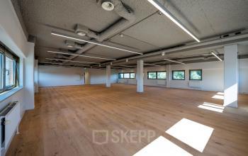Spacious unfurnished office space with large windows and wooden flooring at Joop Geesinkweg 601, Amsterdam Amstel Business Park, ideal for office space rental.