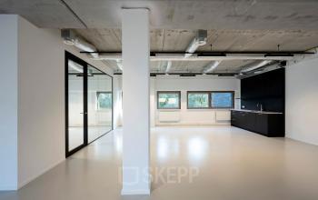 Interior of office section with glass partition, sleek kitchenette, and large windows at Joop Geesinkweg 601, Amsterdam Amstel Business Park.