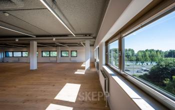 Interior of office space for rent at Joop Geesinkweg 601, Amsterdam Amstel Business Park, featuring natural light and large windows offering park views.