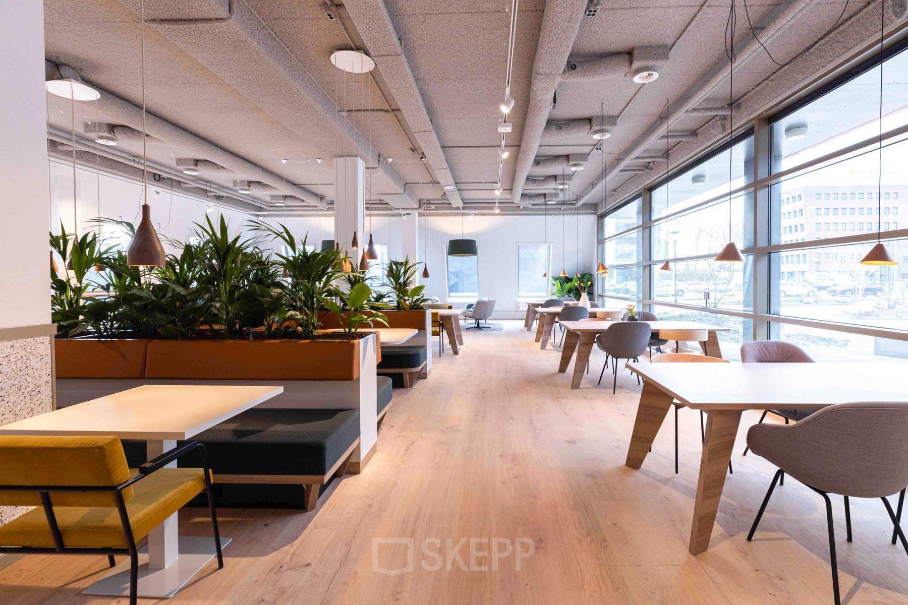 Modern office space rental at Joop Geesinkweg 601, Amsterdam Amstel Business Park with wooden flooring, plants, and natural light from large windows.