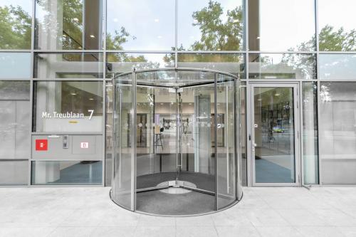 Exterior view of the office building at Mr. Treublaan 7, Amsterdam Amstel, featuring a modern revolving door entrance for office space rental.