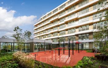 Exterior view of the office building at Willem Fenengastraat 16, Amsterdam Amstel, showcasing modern architecture with a landscaped garden. Ideal location for office space rental with outdoor amenities.