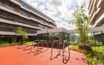 Exterior of office building at Willem Fenengastraat 16, Amsterdam Amstel, showcasing a bike rack on a sunny day with modern office space rental opportunities.