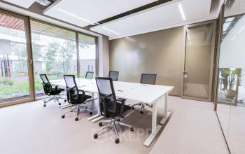 Modern office space rental in Amsterdam Amstel with a large table and chairs, featuring glass walls and natural light.