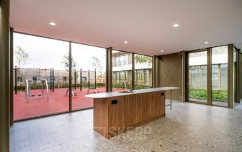 Spacious, light-filled entrance area at Willem Fenengastraat 16 in Amsterdam Amstel, featuring large windows with outdoor views and a modern wooden counter. Ideal for businesses seeking an impressive office space rental.