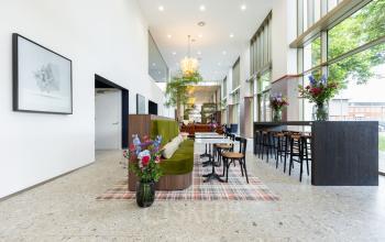 Spacious, well-lit office interior on Willem Fenengastraat 16, Amsterdam Amstel with modern seating and vibrant floral decor, perfect for office space rental.