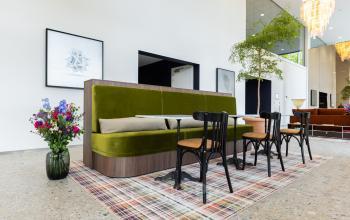 Stylish office space with green velvet seating, wooden chairs, and vibrant decor at Willem Fenengastraat 16. Perfect office space rental in Amsterdam Amstel.