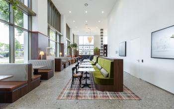 Modern office space with stylish booths and tables, featuring large windows and a minimalist design at Willem Fenengastraat 16, Amsterdam Amstel. Ideal for office space rental.