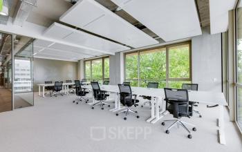 Modern office space rental at Willem Fenengastraat 16, Amsterdam Amstel, featuring large windows and ergonomic chairs around sleek desks.