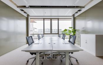 Modern office space in Amsterdam Amstel with large windows, conference tables, and sleek chairs. Ideal for office space rental.