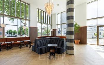 Spacious office lobby at Willem Fenengastraat 16, Amsterdam Amstel, featuring modern furnishings with seating areas and large windows. Ideal for office space rental.