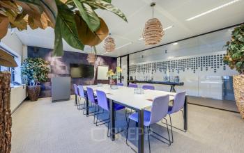 Modern furnished office space at Prins Bernhardplein 200, Amsterdam Amstel, featuring a conference room with a long table and seating for meetings. Ideal for office space rental.